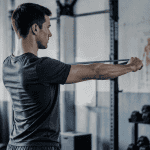 Homme exécutant un band pull apart en salle de sport